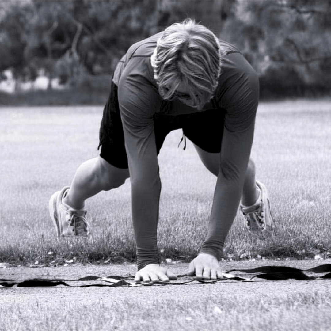 Athlete performing a crawling exercise on a grassy field, showcasing strength and agility, as part of a fitness routine.