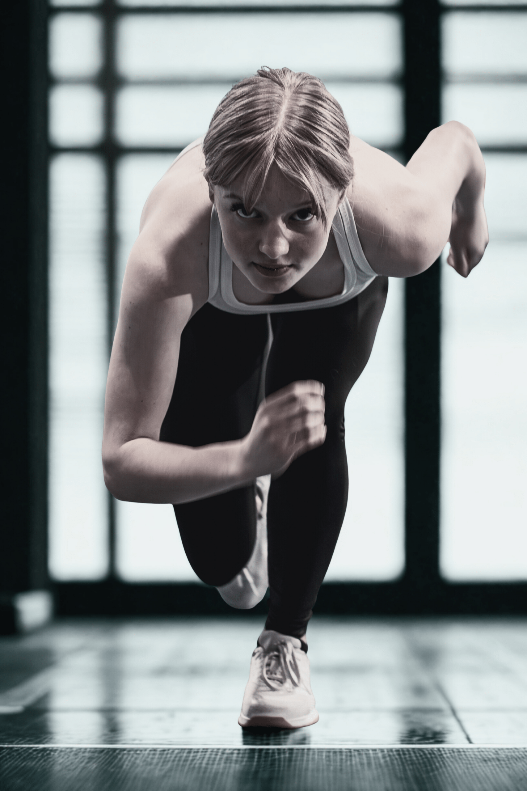 Athlete sprinting on a track, showcasing determination and speed. The focus highlights her intense expression and powerful stance, emphasizing athleticism.